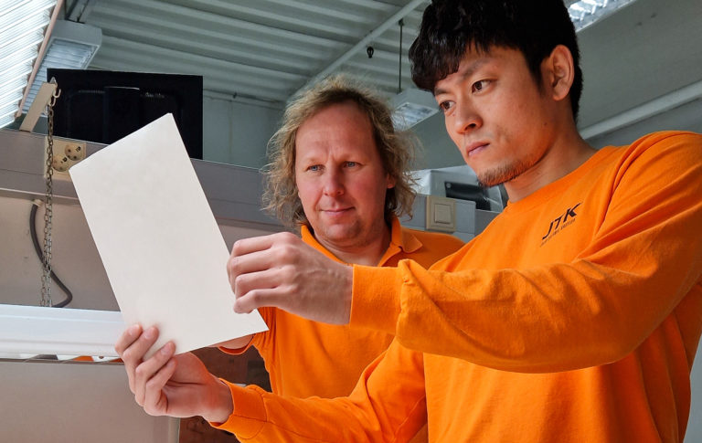 Pekka Peippo ja Kenta Watanabe katsovat yhdessä Kenta Watanaben kädessä pitämää uutta kuitapohjaista pakkausmateriaalia.