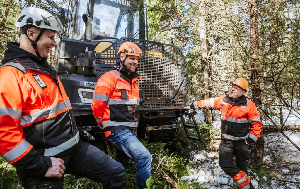 Kai Laaja, Aki Laaja ja metsäkoneen kuljettaja Marko Koppelomäki keskustelevat metsähakkuualueella metsäkoneen vieressä.