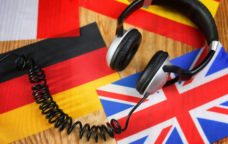 kielikurssin kuulokkeet ja lippu puupöydällä.