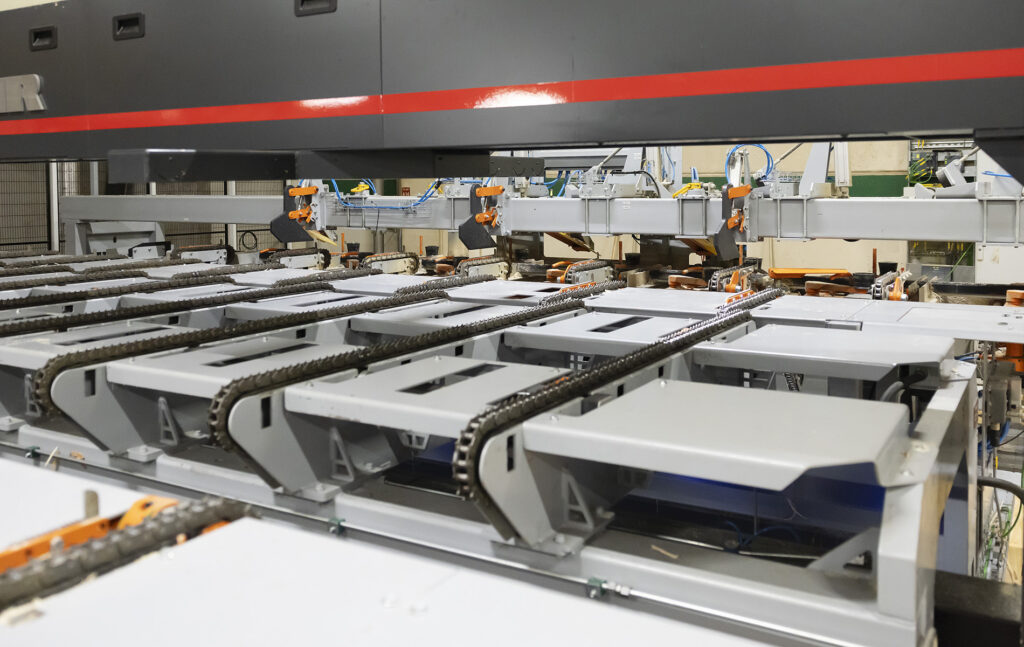 Sahan tuotantolinjan koneisto ja kuljetusjärjestelmä teollisuushallissa.