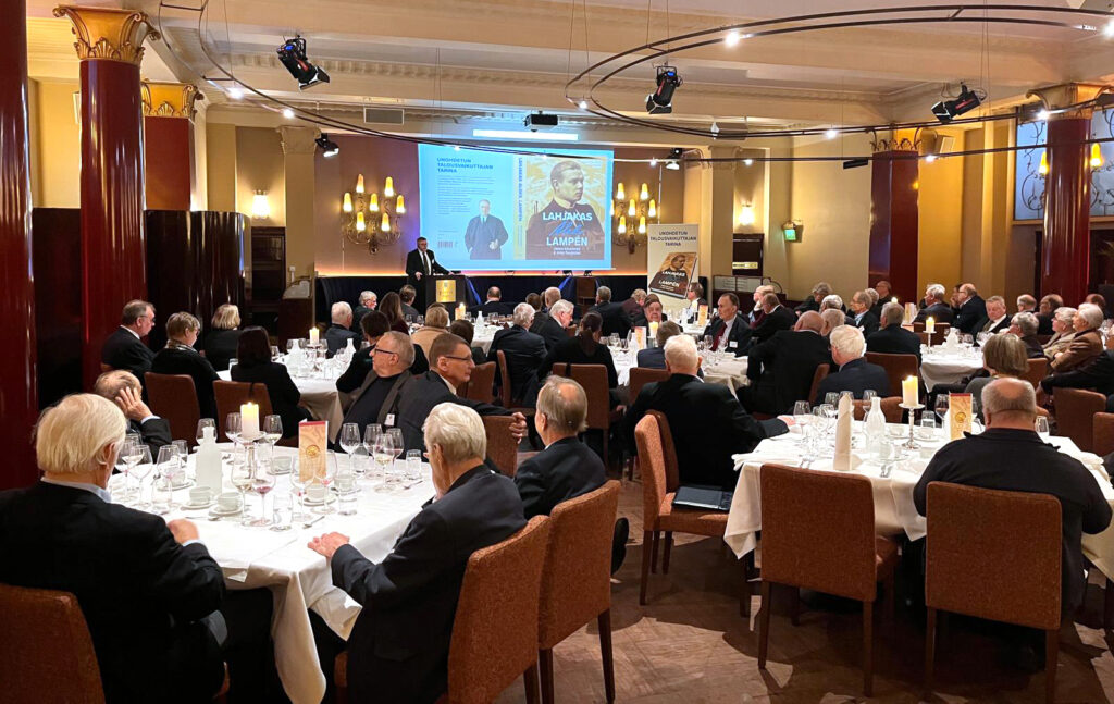 PI:n seniorilounas Pörssitalolla: seniorijäseniä pitkien pöytien ääressä kuuntelemassa esitelmää Aleks. Lampénin elämästä tammikuussa.