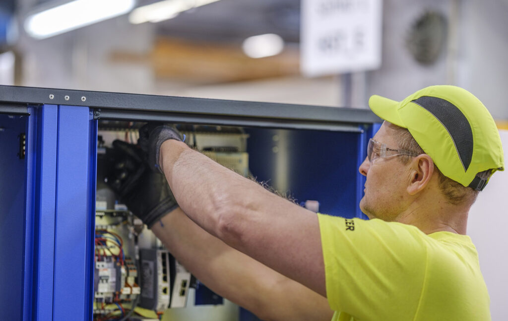 Janek Kaaret asentamassa sähköjä kompressoriin.