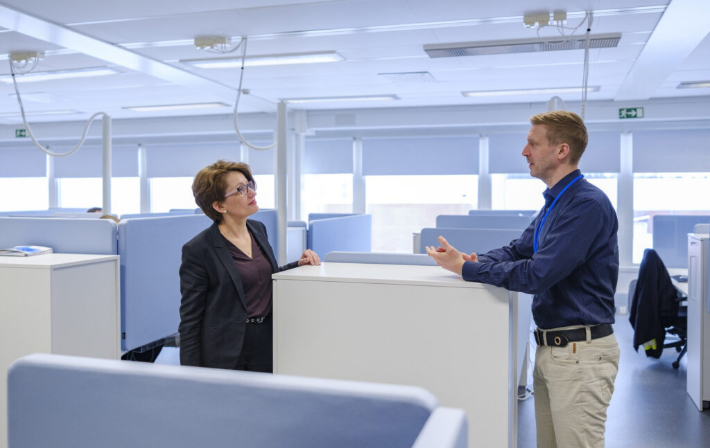 Marja-Leena Mäkinen ja myyntijohtaja Ilari Pakkala pikapalaverissa avokonttorin käytävällä.