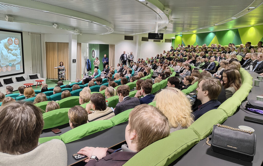 FBI-päivän seminaaritilaisuus, jossa täysi yleisö seuraa lavalla pidettävää esitystä ja valkokangasta auditoriossa.