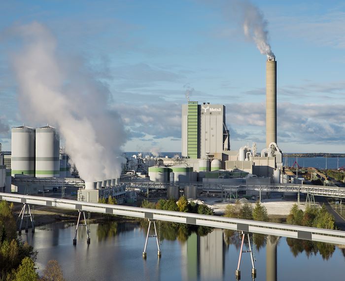 Metsä Groupin tehdasalue ja biotuotetehdas meren rannalla, teollisuuslaitoksen savupiippu ja höyryä ilmassa.