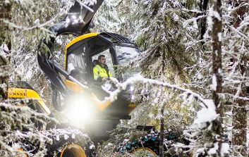 Kuvassa Petri Lahtinen työskentelee metsänhakuukoneen ohjaimissa metsässä.