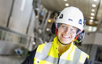 Marjo Santanen katsoo kohti kameraa turvakypärä päässään ja turvaliivi päällään.