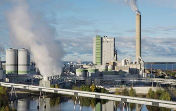 Metsä Groupin tehdasalue ja biotuotetehdas meren rannalla, teollisuuslaitoksen savupiippu ja höyryä ilmassa.