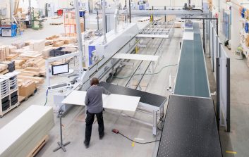 Henkilö työskentelee Woodi Oy.n tuotantohallissa suurikokoisen automaattisen sahakoneen äärellä