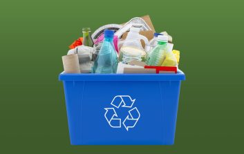 Recycling bin full of mixed materials, paper, plastic, glass and metal isolated on white