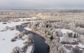 Luminen metsämaisema, jonka keskellä virtaa sula joki.